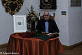 Laureat nagrody im. Skurpskiego Janusz Połom siedzi przy stole. Na stole statuetka i kwiaty.