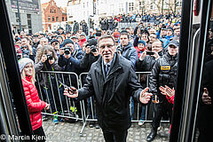 Prezydent Piotr Grzymowicz tuż po przecięciu wstęgi przed tramwajem, w ręku trzyma nożyczki. Za nim tłum olsztynian i fotoreporterów