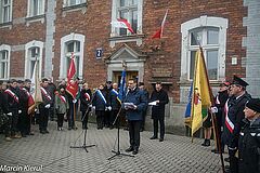 Uroczystości przed kamienicą, w której zamieszkali kolejarze. W półkolu stoją poczty sztandarowe. Do mikrofonu przemawia prezydent Olsztyna Piotr Grzymowicz