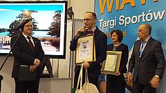 Dyrektor ratuszowej promocji Krzysztof Otoliński odbiera nagrodę podczas Targów Wiatr i Woda.